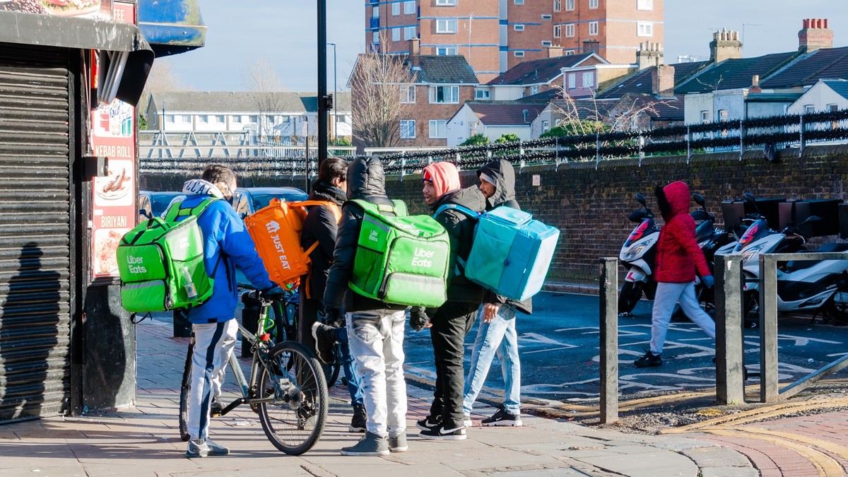 Couriers of fast food, backpack behind, London, United Kingdom, January 04, 2021: Day food delivery. Couriers of fast food, backpack behind his back delivers food from cafes and restaurants do to nati ...