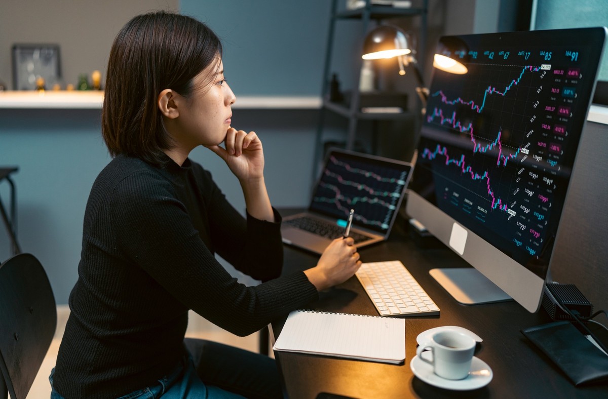A young woman is doing cryptocurrency business trading on her computer at home at nigh.