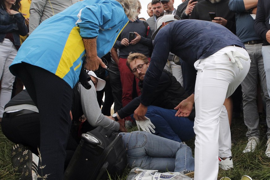 28.09.2018, Frankreich, Paris: Golf: Ryder Cup, Herren: Brooks Koepka (r) vom Team USA gibt einer Zuschauerin seinen Handschuh, nachdem sie von seinem Golfball getroffen wurde, und nun am Boden liegt, ...