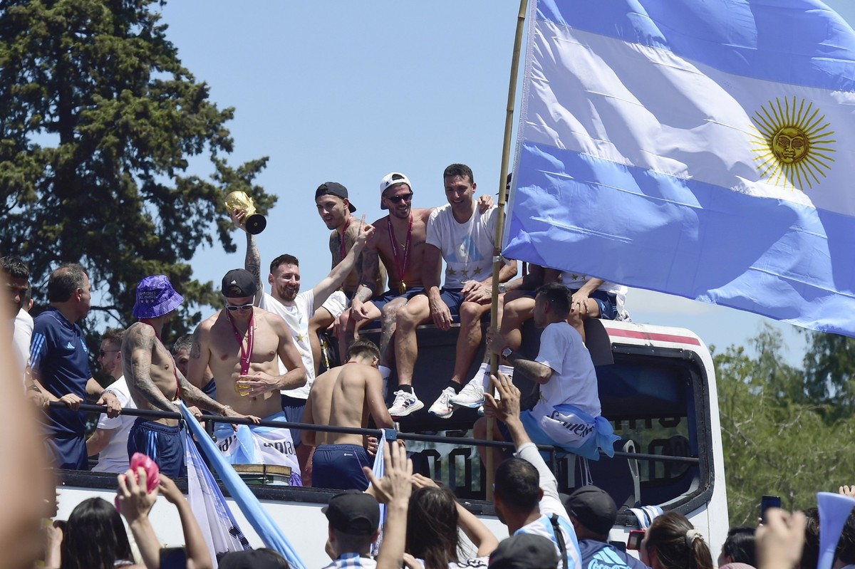 Lionel Messi raises the FIFA World Cup trophy as he rides on an open-top bus with teammates of the Argentine soccer team that won the World Cup tournament in Buenos Aires, Argentina, Tuesday, Dec. 20, ...