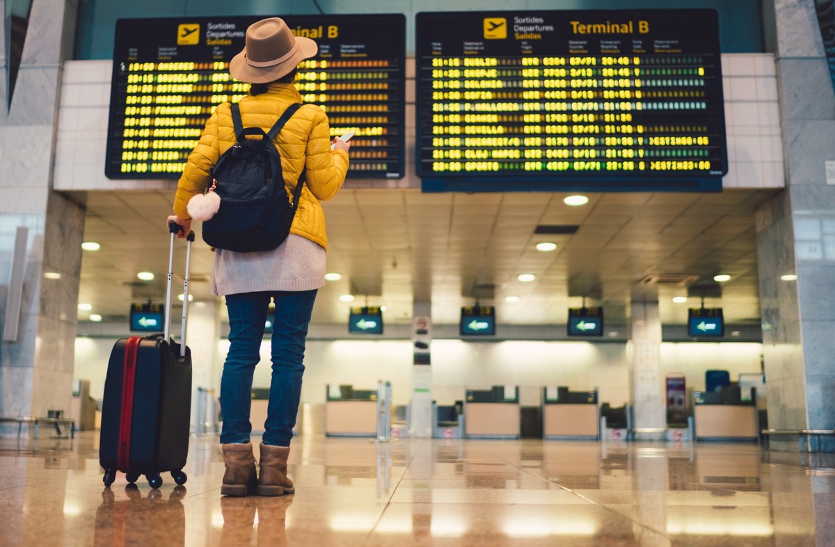 Young woman at the airport in Barcelona checking for the flight schedule