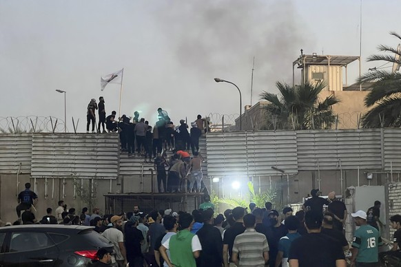 20.07.2023, Irak, Bagdad: Demonstranten erklimmen eine Mauer an der schwedischen Botschaft. Nach Ankündigung einer weiteren geplanten Koranverbrennung in Schweden haben Demonstranten die Botschaft des ...