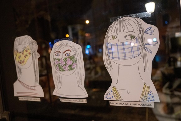 Drei gemalte Köpfe mit der Unterschrift „Bitte Tragen Sie Masken“ kleben am Eingang eines Ladengeschäfts in der Innnenstadt. Nach knapp zwei Jahren ist in großen Teilen Deutschlands die staatliche Vor ...