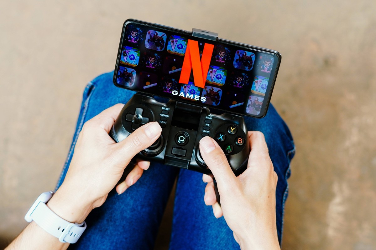 August 8, 2023, Brazil. In this photo illustration, a person playing on a joystick and the Netflix Games logo displayed on a smartphone screen. August 8, 2023, Brazil. In this photo illustration, a pe ...