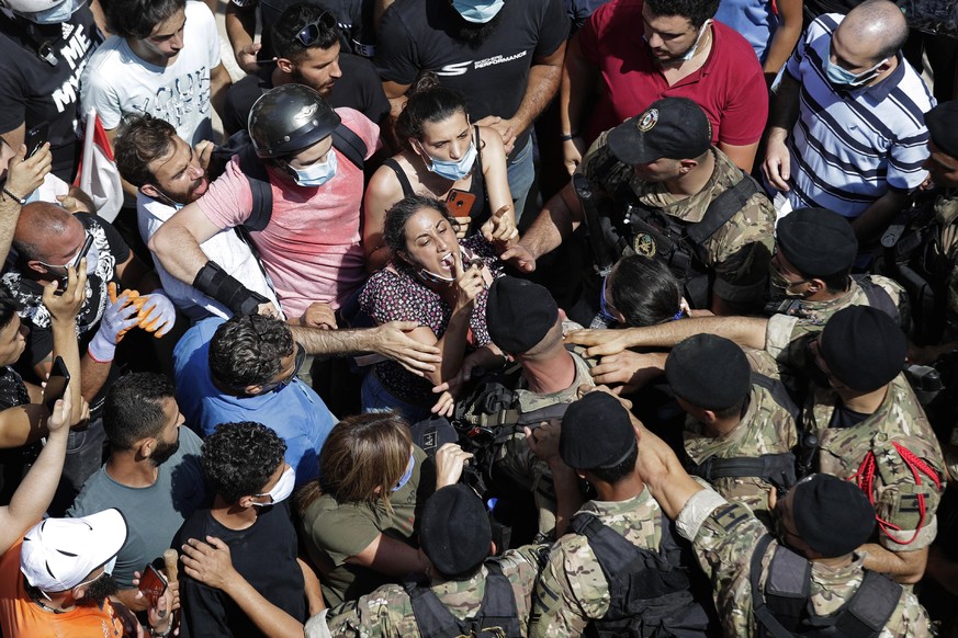 A woman yells at Lebanese soldiers during scuffles with the soldiers who are blocking a road as French President Emmanuel Macron visits the Gemmayzeh neighborhood, which suffered extensive damage from ...