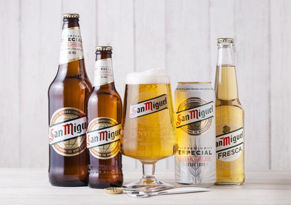 LONDON, UK - APRIL 27, 2018: Glass bottles of San Miguel lager beer on wooden background with original glass. The San Miguel brand of beer is the leading brand of the San Miguel Brewery Inc, the large ...