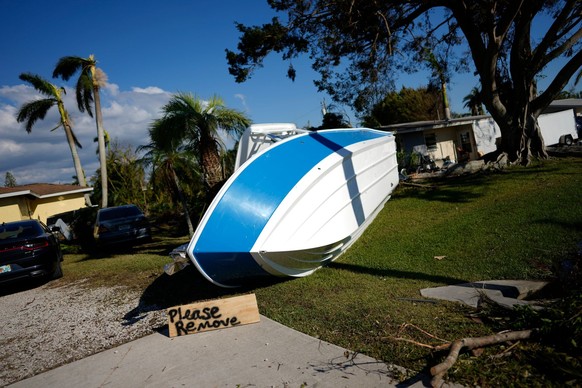 A sign placed by a resident asks that a boat that landed on their lawn during Hurricane Ian please be removed, in south Fort Myers, Fla., Saturday, Oct. 1, 2022. (AP Photo/Rebecca Blackwell)
