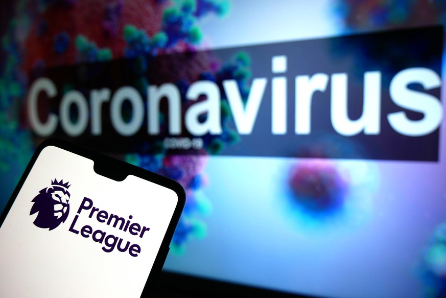 Coronavirus Stock The Premier League logo seen displayed on a mobile phone with an illustrative model of the Coronavirus displayed on a monitor in the background. Photo credit should read: James Warwi ...