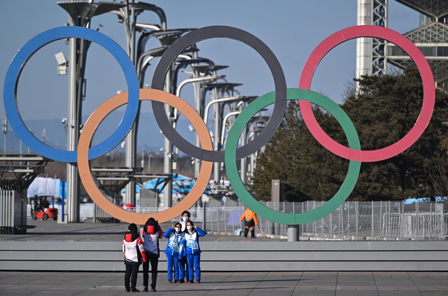 Volunteers stehen vor den olympischen Ringen für ein Selfie. Die Olympischen Winterspiele in Peking finden vom 04.-20.02.2022 unter strengen Corona-Auflagen statt.