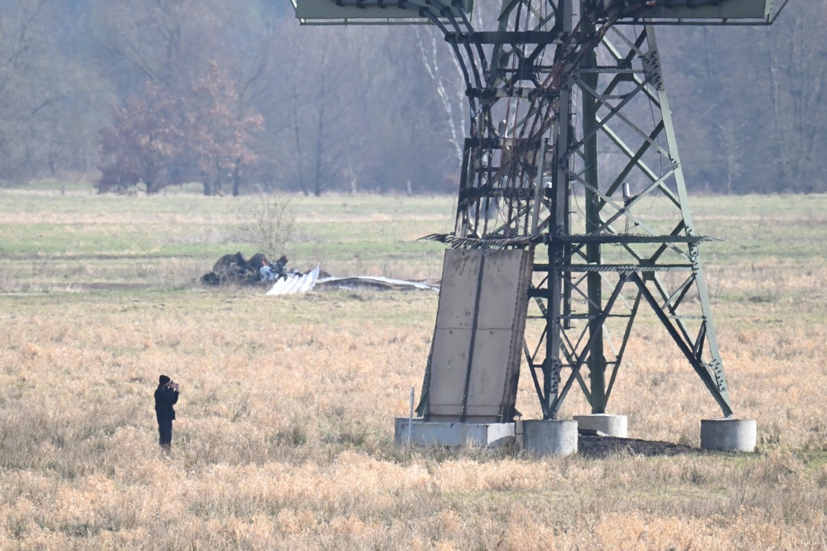 05.03.2024, Brandenburg, Spreenhagen: Ein verbrannter Strommast steht auf einem Feld und ein Polizeifotograf dokumentiert die Spuren. In der Tesla-Autofabrik in Gr�nheide steht die Produktion wegen de ...