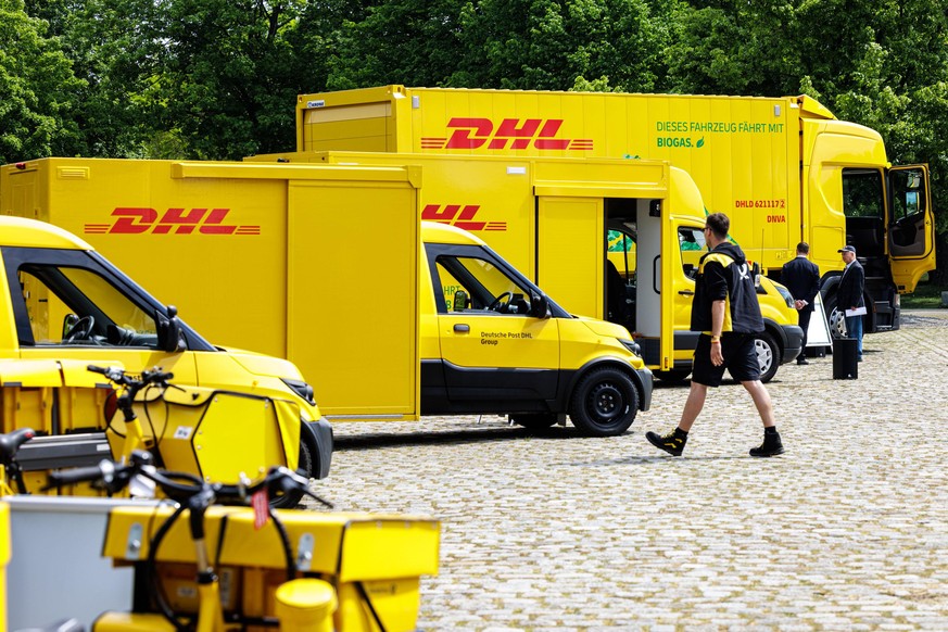 HANDOUT - 11.05.2022, Berlin: Verschiedene Fahrzeuge der Deutsche Post DHL mit alternativen Antrieben stehen auf öffentlichen Platz. Ganz hinten steht ein mit Biogas betriebener Lastwagen, davor stehe ...