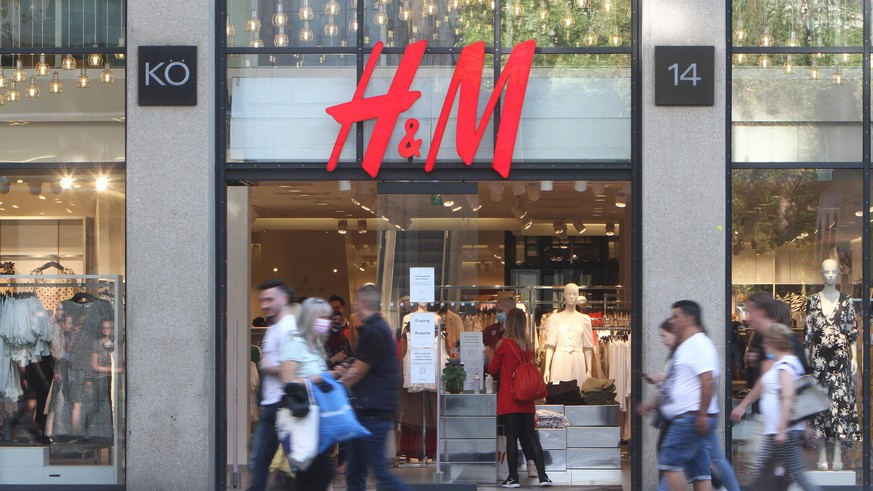 Passanten gehen an einer H &amp; M Hennes Mauritz Filiale in der Fußgängerzone und Einkaufsstraße Königstraße in der Innenstadt von Stuttgart vorbei, Baden Württemberg, Deutschland *** Passers-by walk ...