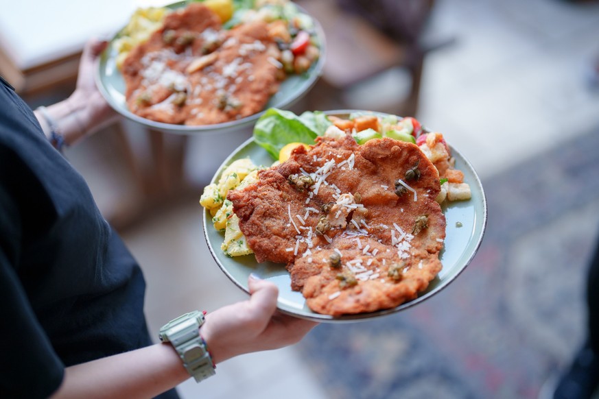 The waiter serving schnitzel on a plate