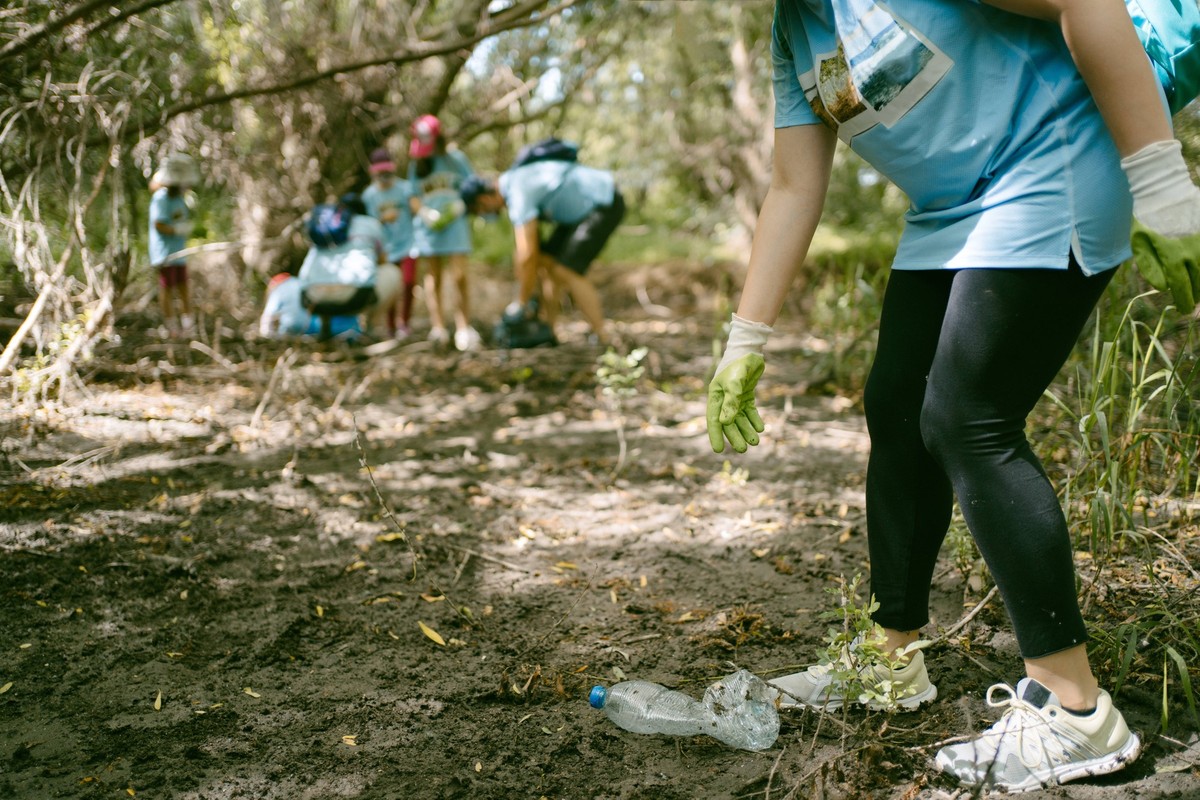 Crop anonymous activist in protective gloves picking plastic bottle from ground while collecting garbage in nature, Property released AlvaroSanchez_EnvironmentalGathering_21.jpg Copyright: xAlvaroxSan ...