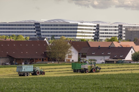 Im Vordergrund arbetiet die lokale Landwirtschaft, im Hintergrund das Adidas Hauptgebäude