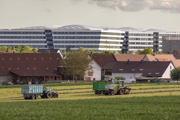 �rtliche Landwirtschaft und Weltfirmen Die Geb�ude des Adidas Campus, davor die kleine Ortschaft Haundorf, die zu Herzogenaurach geh�rt, und davor wird mit gro�em M�hdrescher eine gro�e Wiese gem�ht H ...