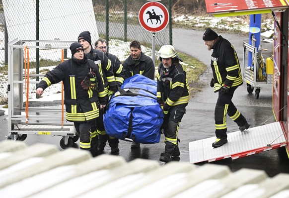 12.03.2023, Nordrhein-Westfalen, Freudenberg: Feuerwehrleute entladen ihre Ausrüstung für den Einsatz nahe des Fundorts einer Leiche. Nach dem Fund eines weiblichen Leichnams in einem Waldstück ist di ...
