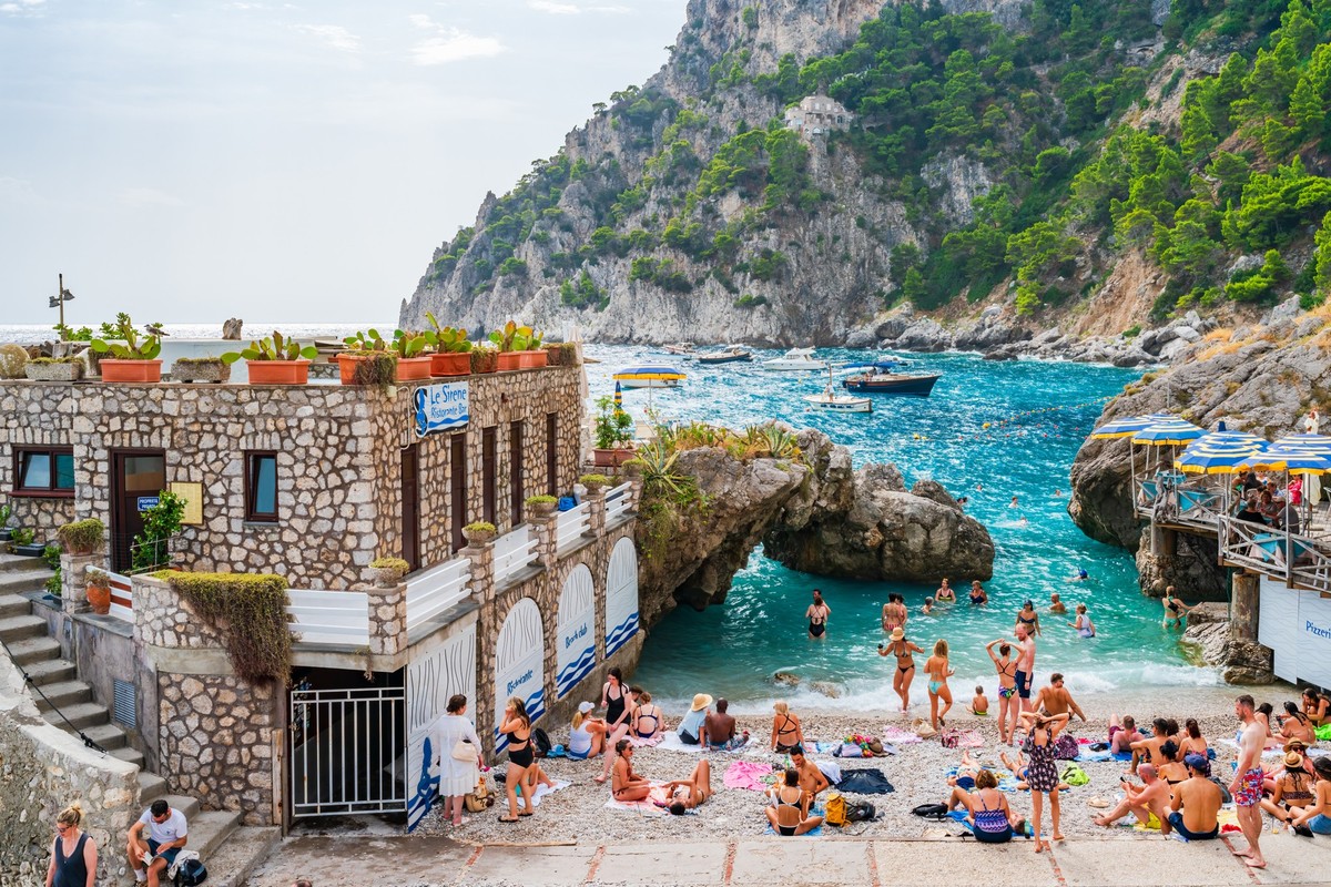 CAPRI, ITALY - SEPTEMBER 22, 2023: Holiday makers relax at Marina Piccola on Capri Island, famed for rugged landscape, upscale hotels and luxury designer shopping Model Released Property Released xkwx ...