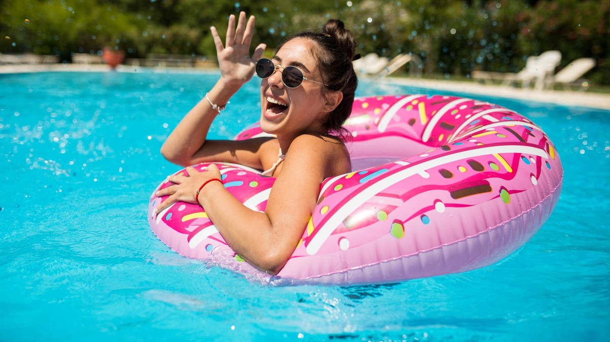 A beautiful girl in the pool on an inflatable donut is having fun on a hot summer day