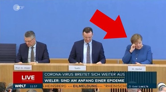 Merkel fasst sich bei einer Pressekonferenz ins Gesicht.