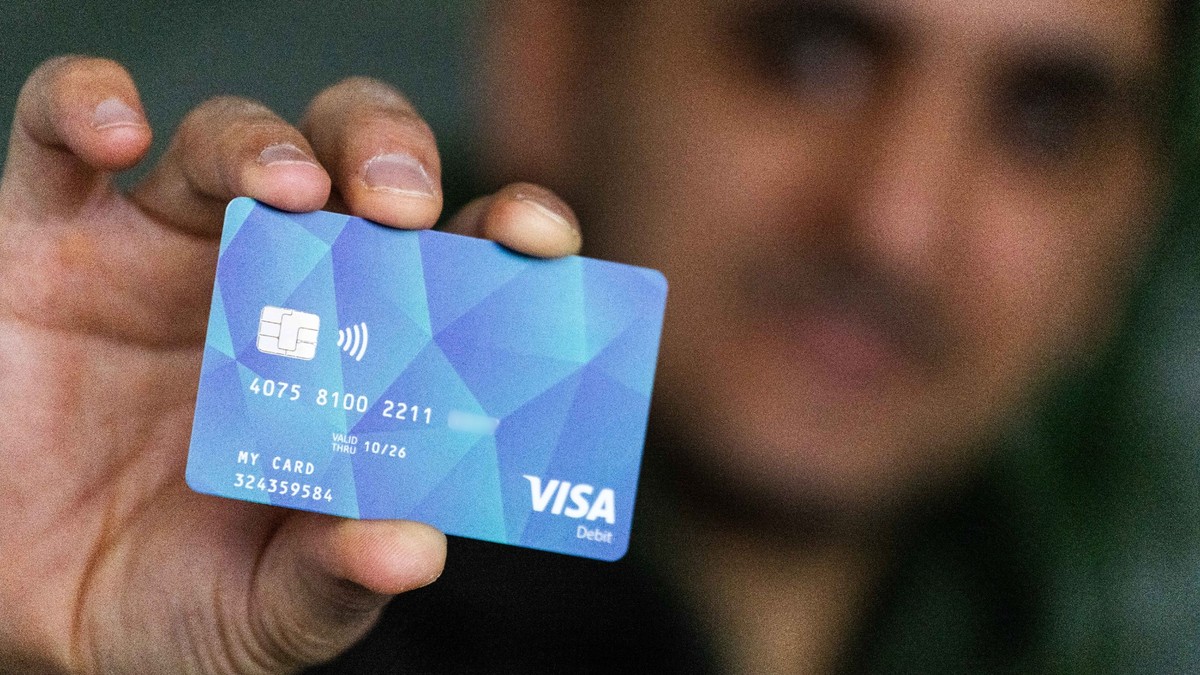 PRODUKTION - 17.01.2024, Baden-Württemberg, Offenburg: Ein Geflüchteter hält eine Debitcard in der Hand. Der Ortenaukreis zwischen Rhein und Schwarzwald will von diesem Dienstag an die ersten Bezahlka ...