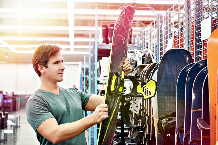 Man chooses a snowboard in sport store