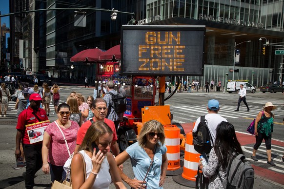 01.09.2022, USA, New York: Passanten gehen am 1. September an einem Schild mit der Aufschrift &quot;Waffenfreie Zone&quot; in der N�he des Times Square vorbei. Rund um den New Yorker Times Square darf ...