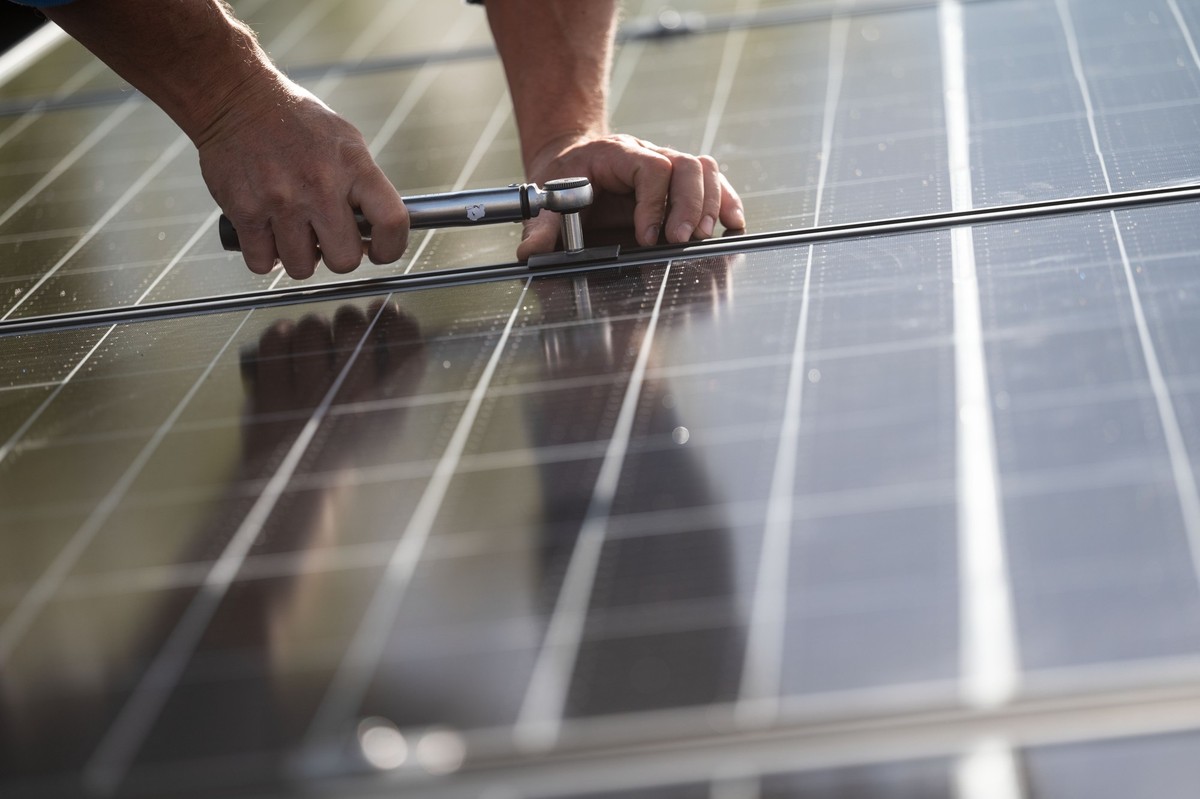 ARCHIV - 13.10.2021, Baden-Württemberg, Stuttgart: Mitarbeiter einer Firma montieren Photovoltaikmodule auf dem Dach eines Wohnhauses. Die zuletzt stark gesunkenen Großhandelspreise für Solarmodule ma ...
