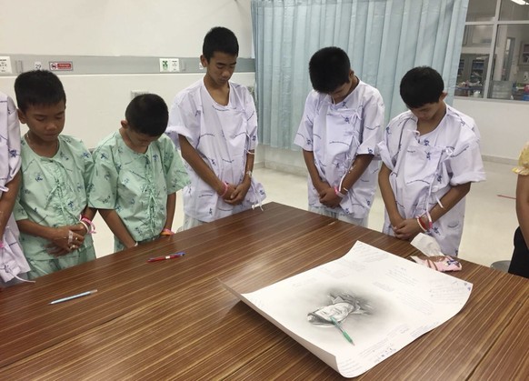In this photo released by Thailand&#039;s Ministry of Health and the Chiang Rai Prachanukroh Hospital, some of the rescued soccer team members bowing their heads respectfully in front of a sketch of t ...