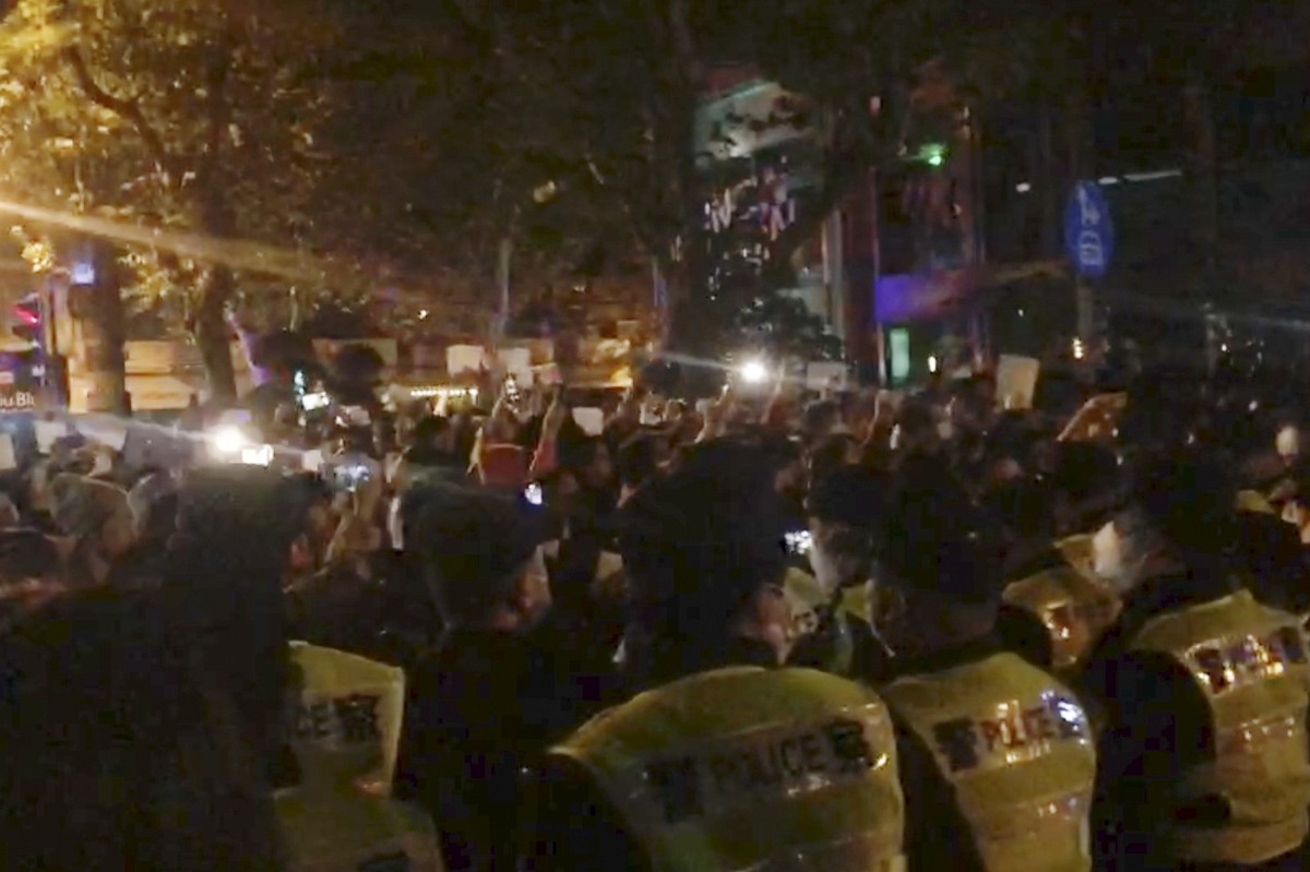 dpatopbilder - SCREENSHOT - 27.11.2022, China, Shanghai: In diesem Bild aus einem Video, das The Associated Press erhalten hat, beobachtet die Polizei (im Vordergrund) die Demonstranten in Shanghai. I ...