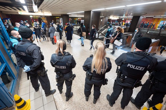 Polizeibeamte stehen in Frankfurt am Main während einer Kontrolle der 3G-Maßnahmen im ÖPNV am Bahnsteig.