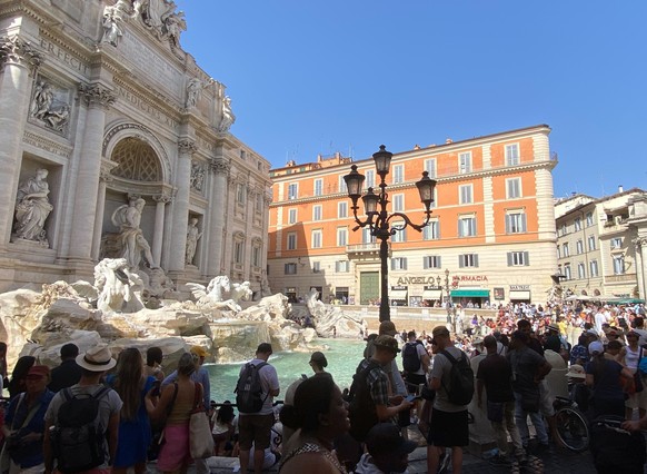 18.07.2023, Italien, Rom: Touristen stehen im Schatten am Trevibrunnen (Fontana di Trevi) auf der Piazza di Trevi. Foto: Robert Messer/dpa +++ dpa-Bildfunk +++