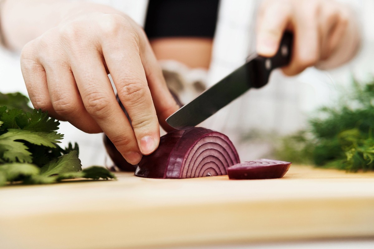 Female hands with knife slicing red onion on wooden cutting board Closeup of female hands with knife slicing red onion on wooden cutting board ,model released, Symbolfoto Copyright: xZoonar.com/Anatol ...