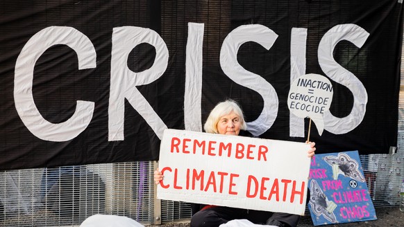 Eine Aktivistin sitzt bei einer Protestaktion der Umweltschutzbewegung Extinction Rebellion für die Todesopfer des Klimawandels vor dem Gelände der UN-Klimakonferenz COP26. In Glasgow ringen rund 200  ...