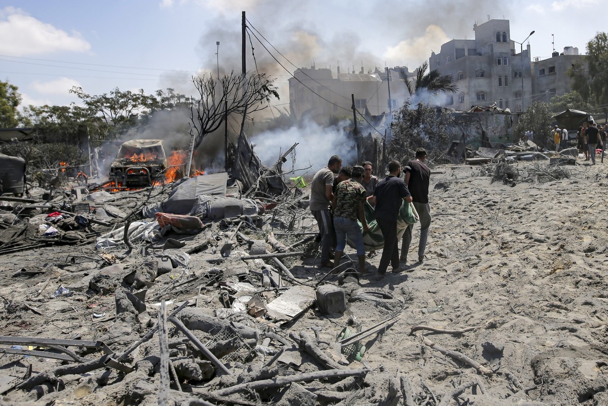 FILE - Palestinians evacuate a body from a site hit by an Israeli bombardment on Khan Younis, southern Gaza Strip, on July 13, 2024. Israel said it targeted Hamas' military commander Mohammed Dei ...