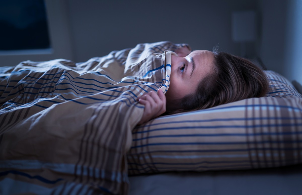 Scared woman hiding under blanket. Afraid of the dark. Unable to sleep after nightmare or bad dream. Awake in the middle of the night in bedroom at home. Monster under the bed or in closet. model rele ...
