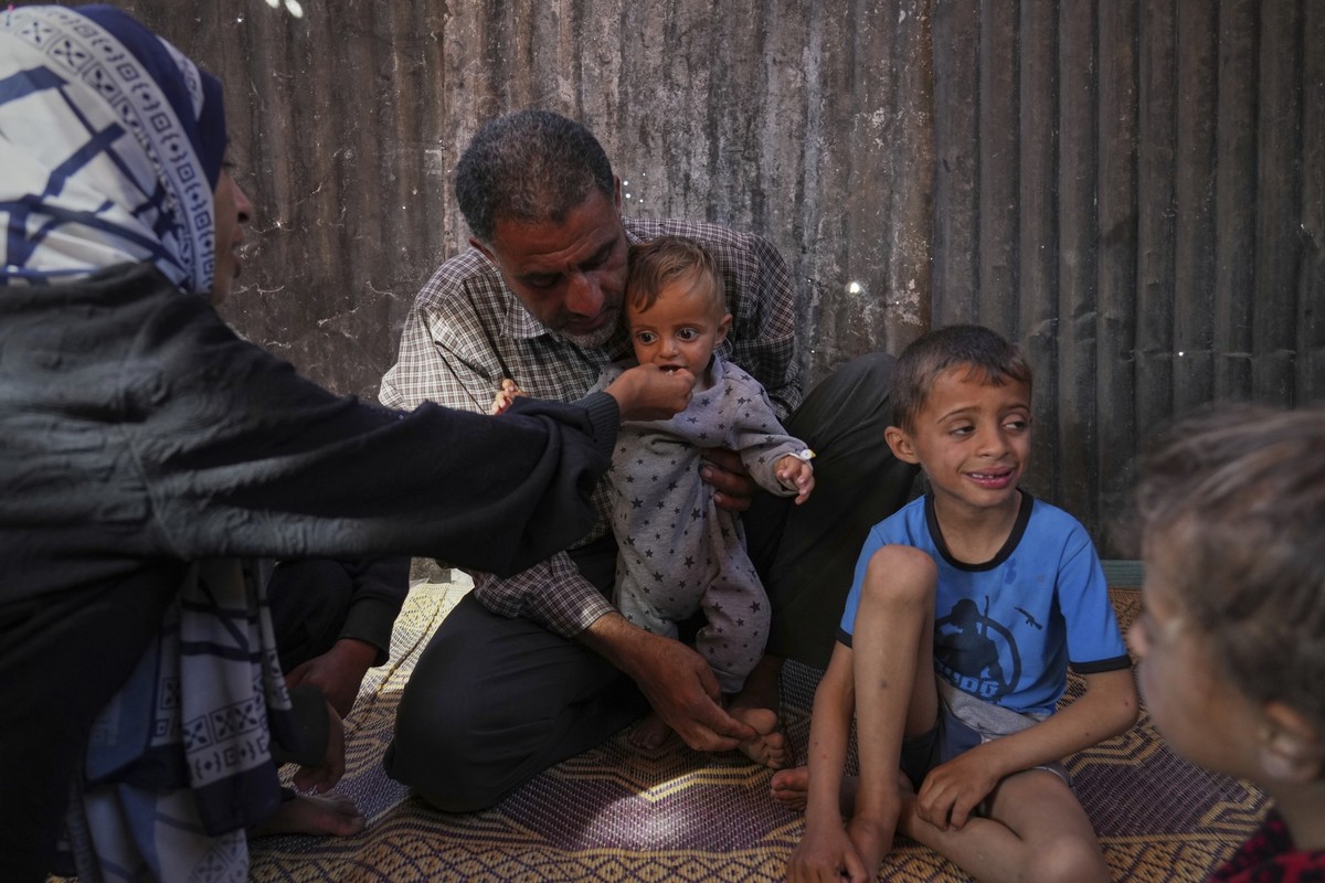Wedad Abdelaal and her husband Ammar , feed their 9 month old son Khaled, in their tent at a camp for displaced Palestinians in Mawasi Khan Younis, Gaza Strip, Friday, May 2, 2025. (AP Photo/Abdel Kar ...