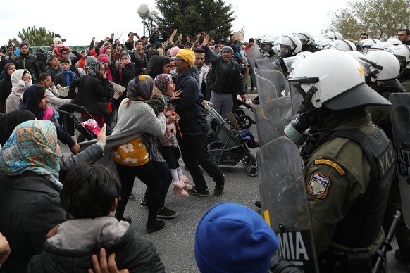 A woman holding a child (C) shouts as refugees and migrants confront riot police during a demonstration outside the Kara Tepe camp, on the island of Lesbos, Greece, February 3, 2020. REUTERS/Elias Mar ...