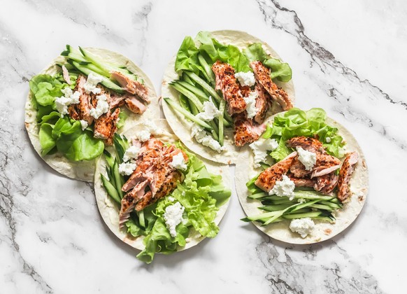 Grilled salmon, iceberg lettuce, cucumber and homemade mayonnaise tacos sauce on a light background. Delicious appetizer, tapas