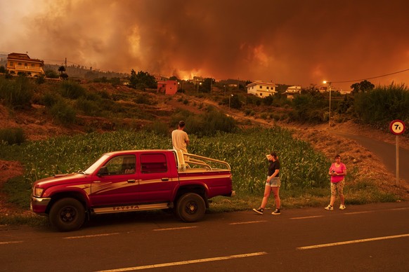 19.08.2023, Spanien, La Orotava: Anwohner versuchen ihre Häuser im Dorf Benijos zu erreichen, während die Polizei das Gebiet abriegelt. Der Waldbrand auf der kanarischen Insel Teneriffa ist nach noch  ...