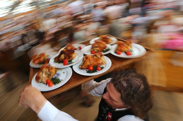 ARCHIV - 19.09.2015, Bayern, M�nchen: Ein Kellner tr�gt auf dem Oktoberfest Hendl (H�hnchen) auf einem Tablett durch ein Bierzelt. (zu dpa: Vegane Wei�wurst und Seitangulasch: Fleischlos auf der Wiesn ...