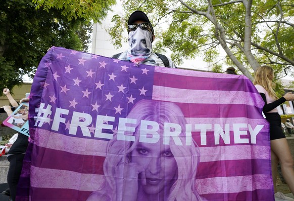 ARCHIV - 29.09.2021, USA, Los Angeles: Carlos Morales aus Los Angeles h�lt eine amerikanische Flagge mit einem Bild von S�ngerin Britney Spears und dem Hashtag #FreeBritney vor dem Stanley Mosk Courth ...