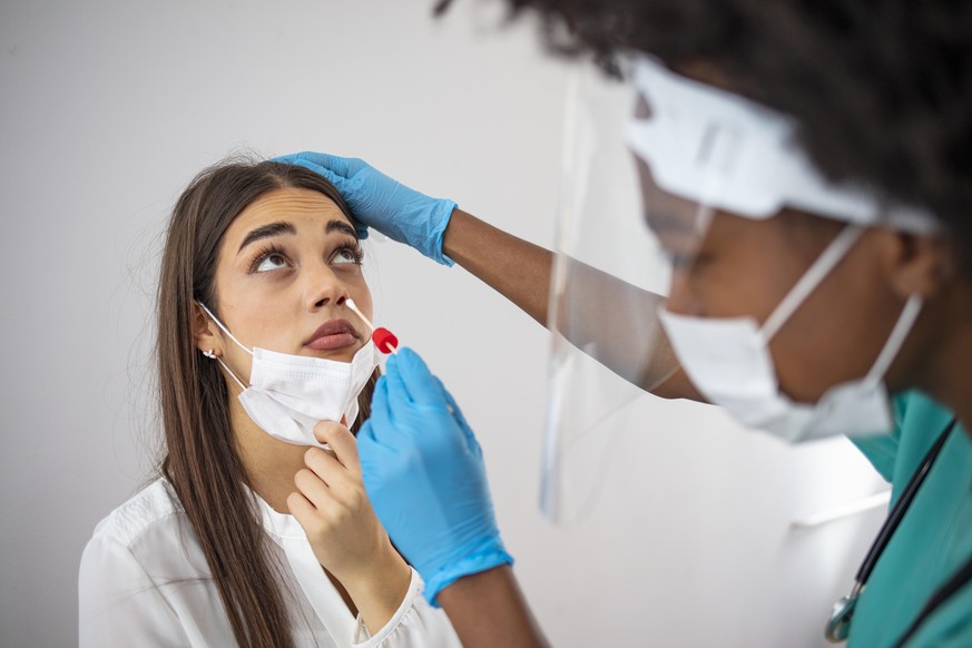 Doctor laboratory assistant in protective suit takes swab from nose of sick patient at home. Laboratory tests for coronavirus concept. Coronavirus test. Medical worker taking a swab for corona virus s ...