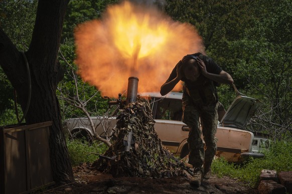 A Ukrainian soldier covers his ears while firing a mortar at Russian positions on the frontline near Bakhmut, Donetsk region, Ukraine, Monday, May 29, 2023. (AP Photo/Efrem Lukatsky)